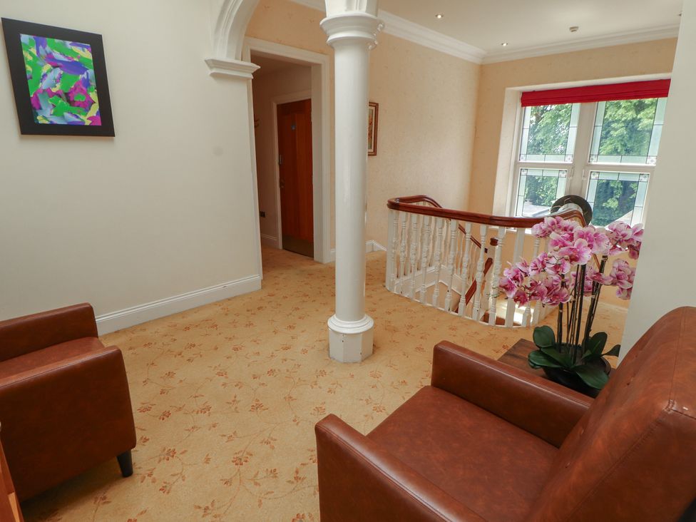 A hallway with chairs and a plant at Eden Lodge in Bardsea