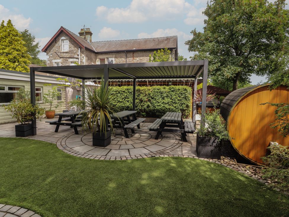 An outdoor seating area with a pergola and dining table at Eden Lodge in Bardsea
