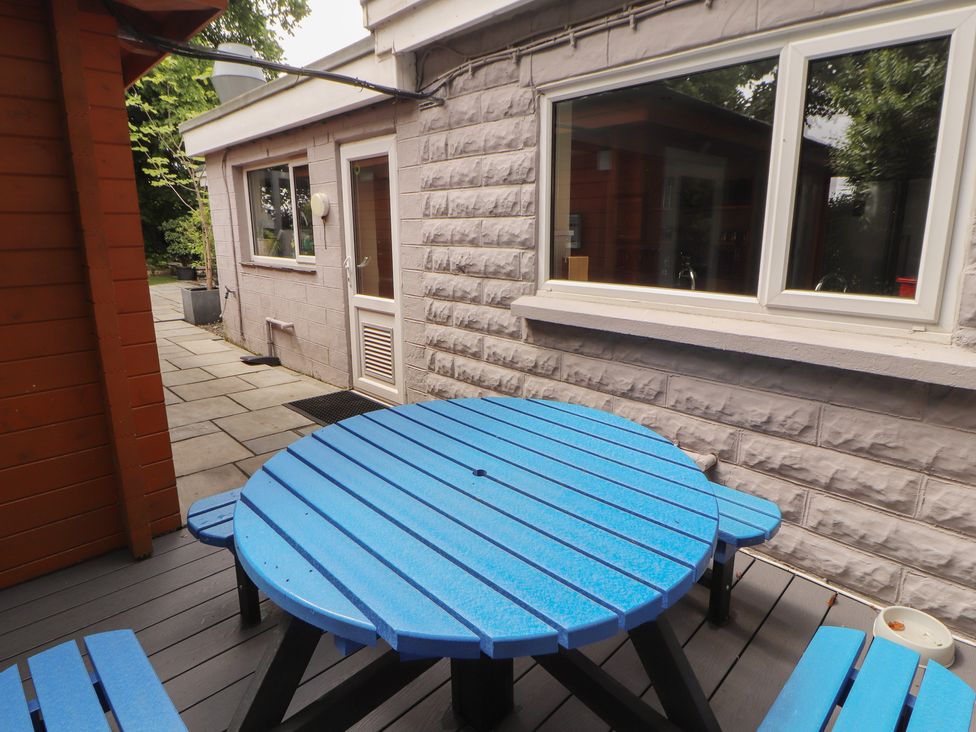An outdoor area with a blue circular table and a stone pathway at Eden Lodge in Bardsea