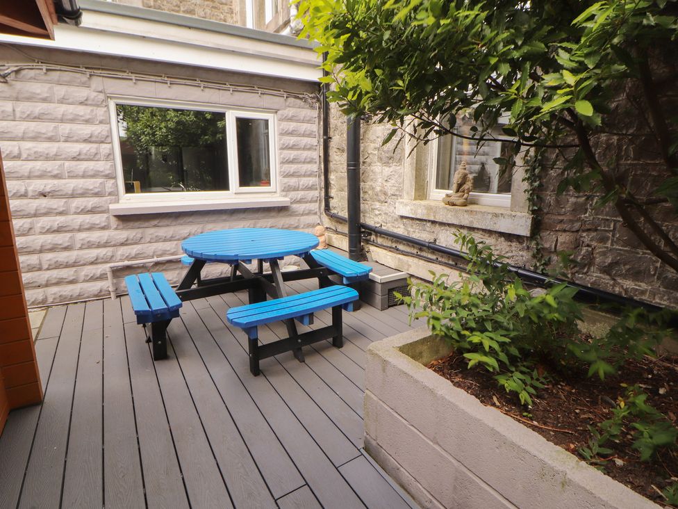 An outdoor seating area with a round blue table and benches at Eden Lodge in Bardsea