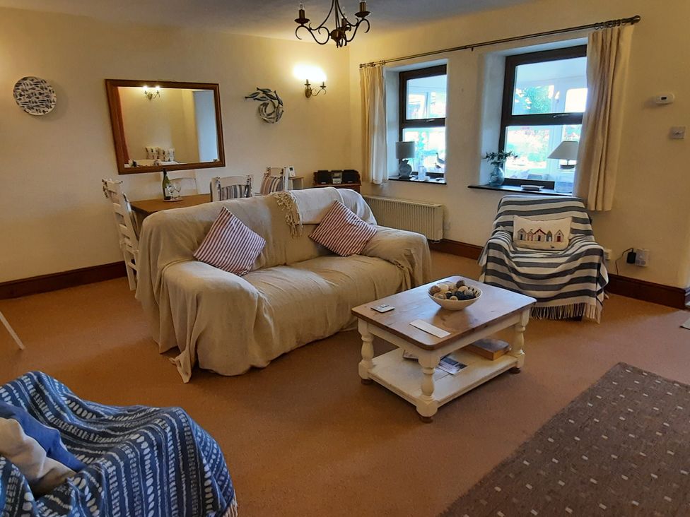 A living room with a sofa, dining table, and coffee table at 4 Cliff Cottages