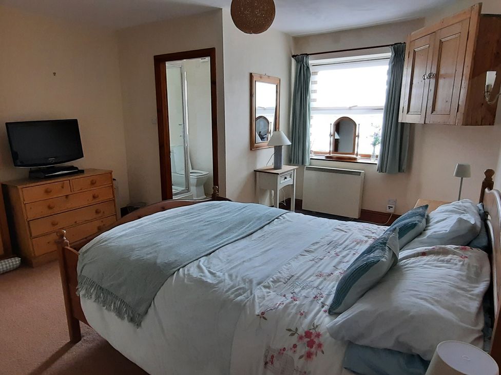 A bedroom with a bed and television at 4 Cliff Cottages