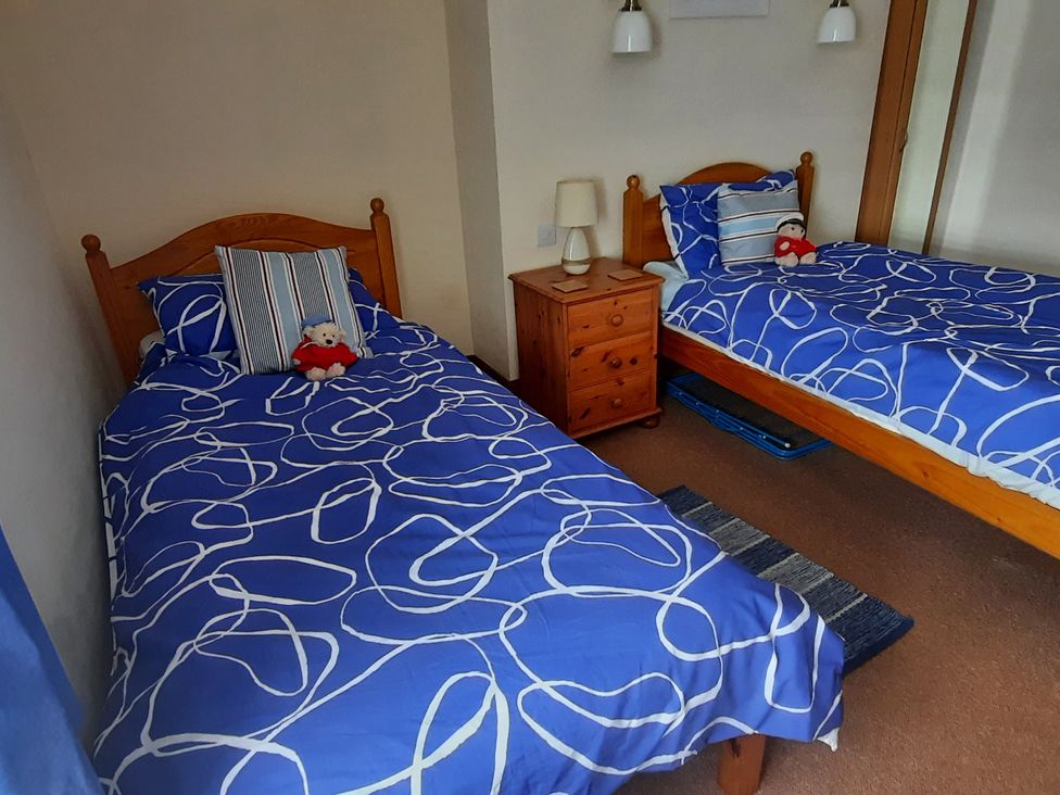 A bedroom with two beds and a bedside table at 4 Cliff Cottages