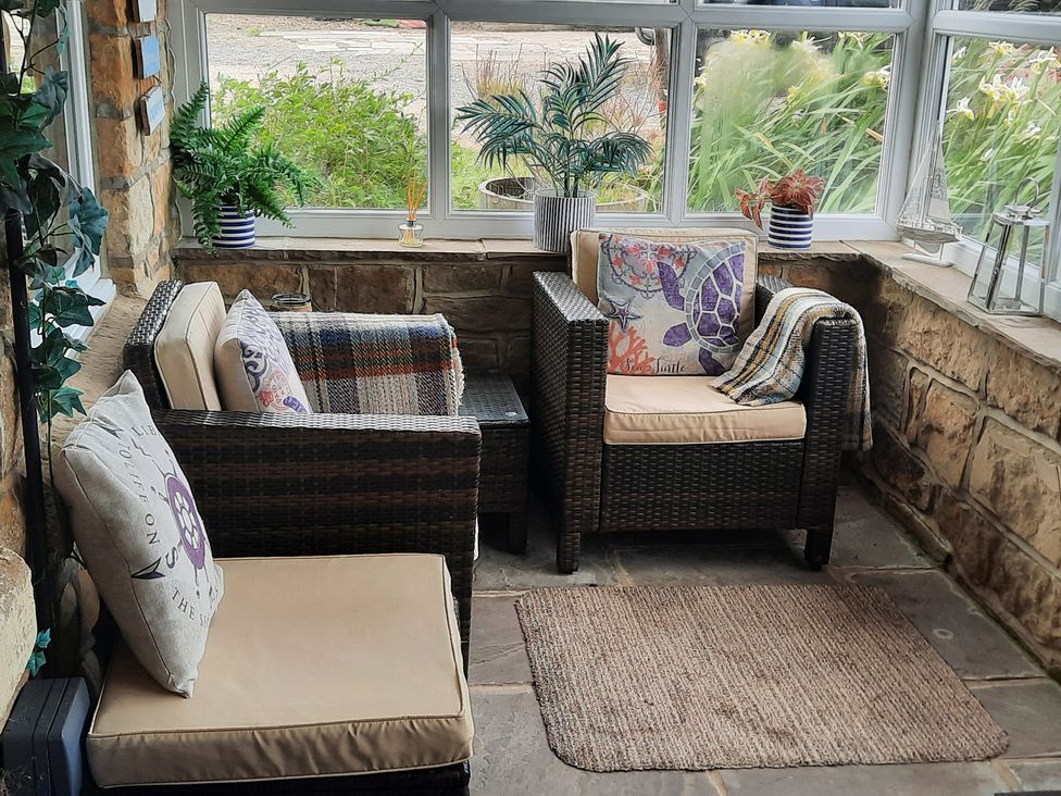 A conservatory with seating and plants at 4 Cliff Cottages