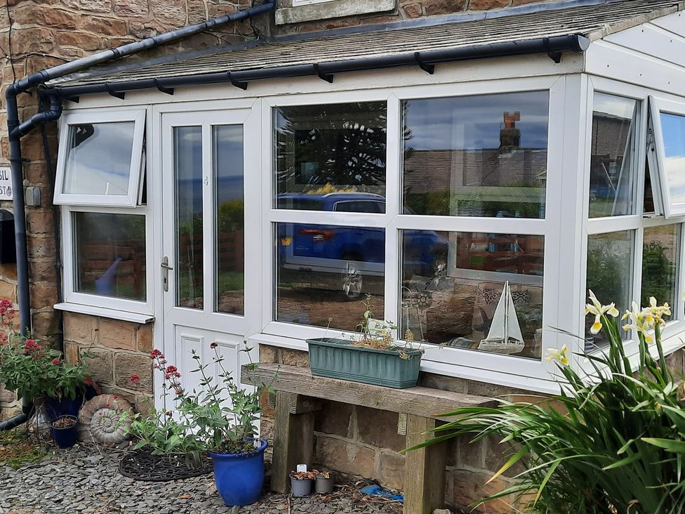 A conservatory entrance with flowers and a table at 4 Cliff Cottages