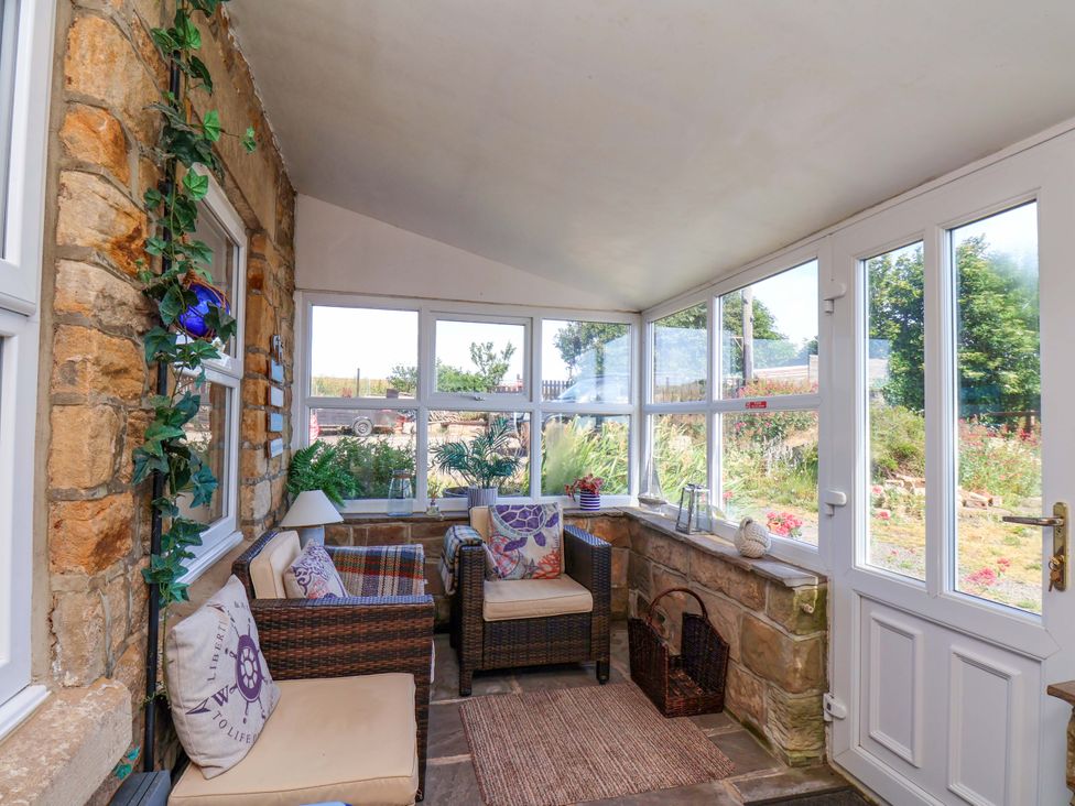 A conservatory with seating and plants at 4 Cliff Cottages Port Mulgrave near Staithes