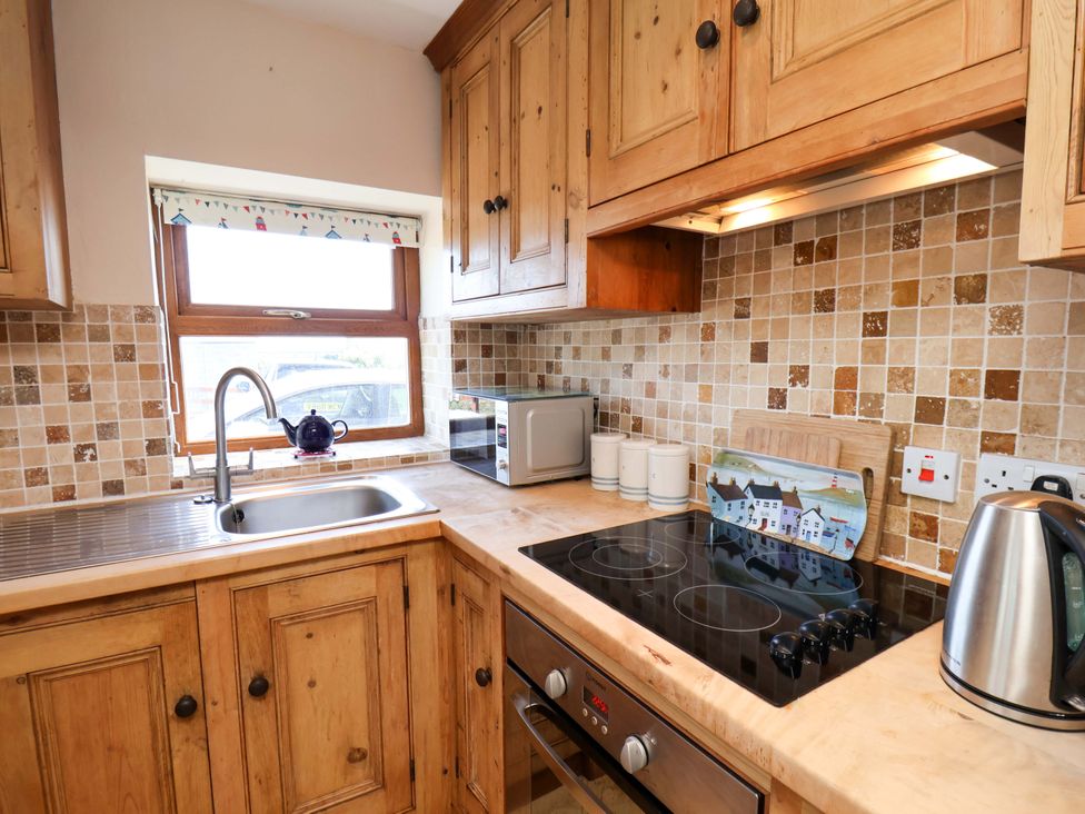 A kitchen with wooden cupboards and appliances at 4 Cliff Cottages in Port Mulgrave near Staithes