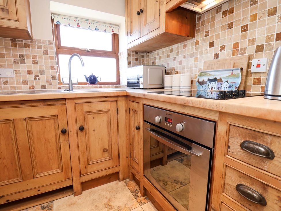A kitchen with wooden cabinets and appliances at 4 Cliff Cottages Port Mulgrave near Staithes