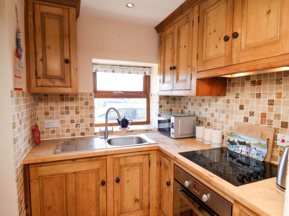 A kitchen with wooden cabinets and a sink at 4 Cliff Cottages Port Mulgrave near Staithes