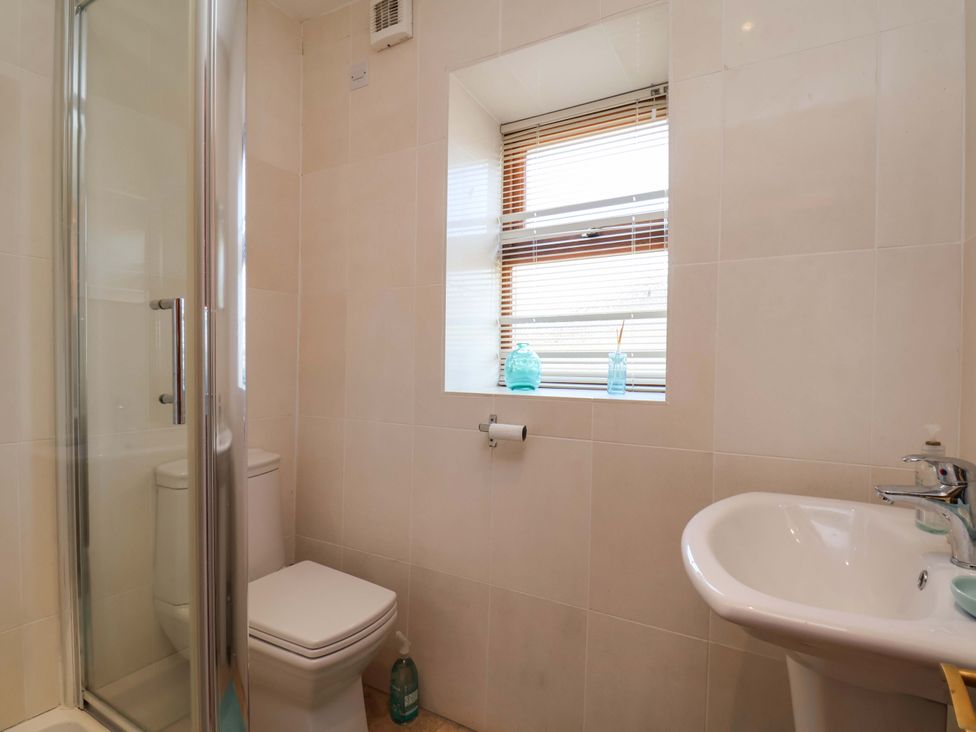 A bathroom with a shower, toilet, and sink at 4 Cliff Cottages in Port Mulgrave near Staithes