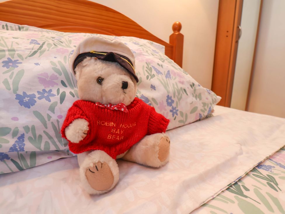 A teddy bear on a bed with floral bedding at 4 Cliff Cottages Port Mulgrave near Staithes