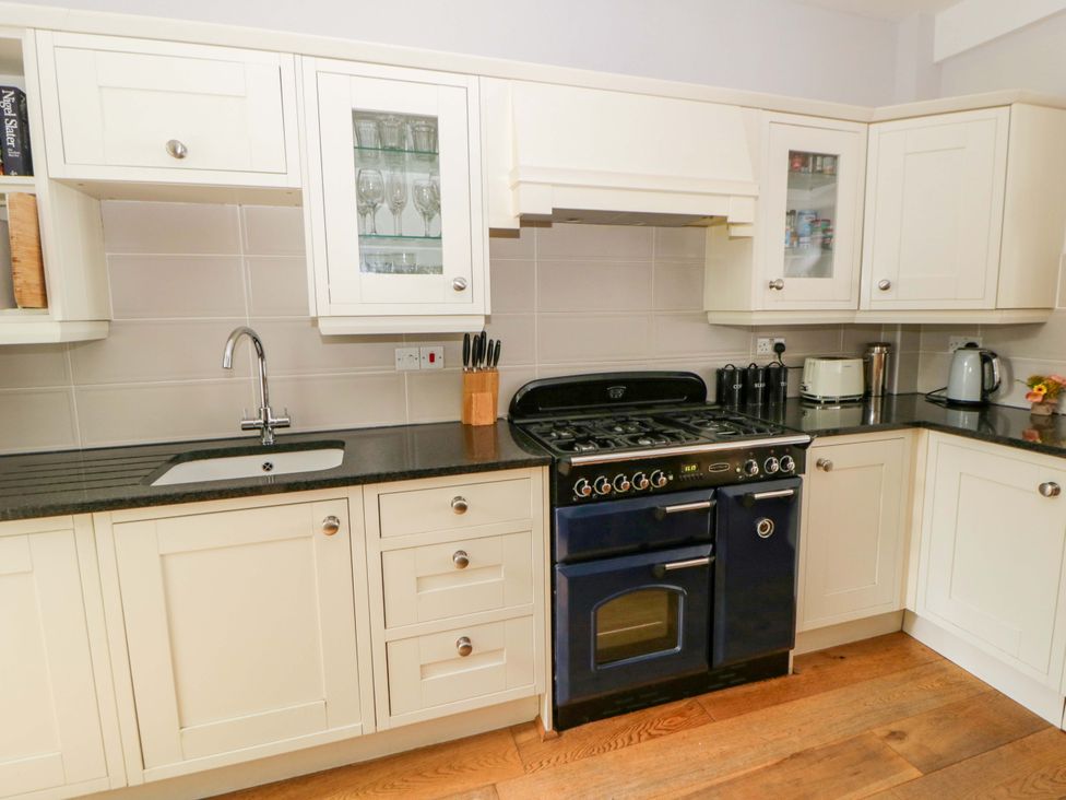 A kitchen with cabinets, a sink, and a stove at Rose Cottage in St Dogmaels near Cardigan