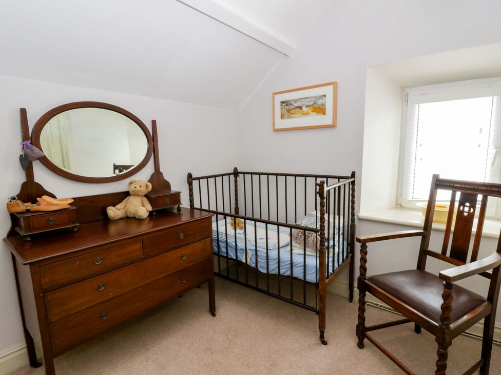 A nursery with a crib and dresser at Rose Cottage in St Dogmaels near Cardigan