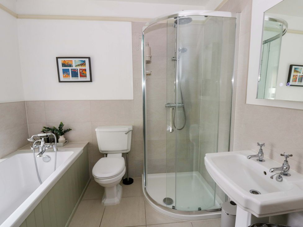A bathroom with a bathtub, shower, toilet, and sink at Rose Cottage in St Dogmaels near Cardigan