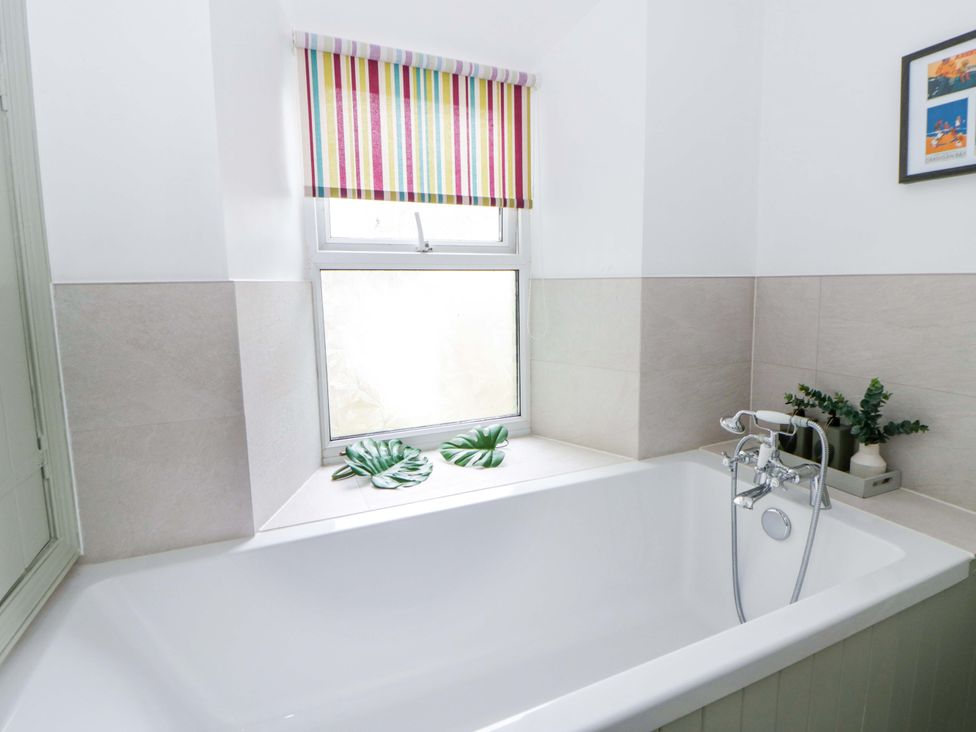 A bathroom with a bathtub and a window at Rose Cottage in St Dogmaels near Cardigan