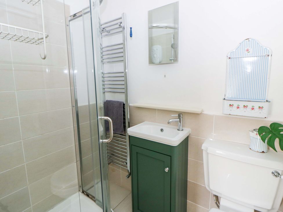 A bathroom with a shower, sink, and toilet at Rose Cottage in St Dogmaels near Cardigan