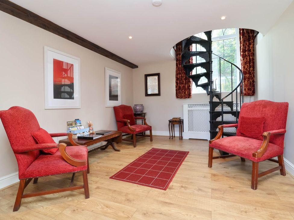 A living room with red chairs and a staircase at Old Chapel in Clovelly