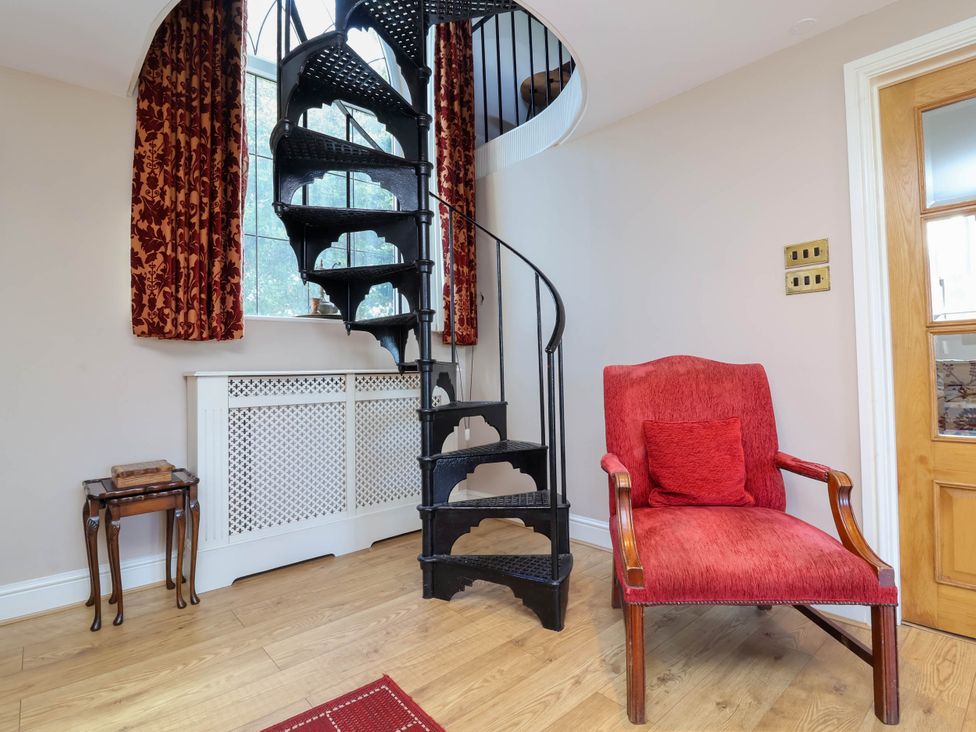 An entrance hall with a spiral staircase and a red chair at The Old Chapel in Clovelly