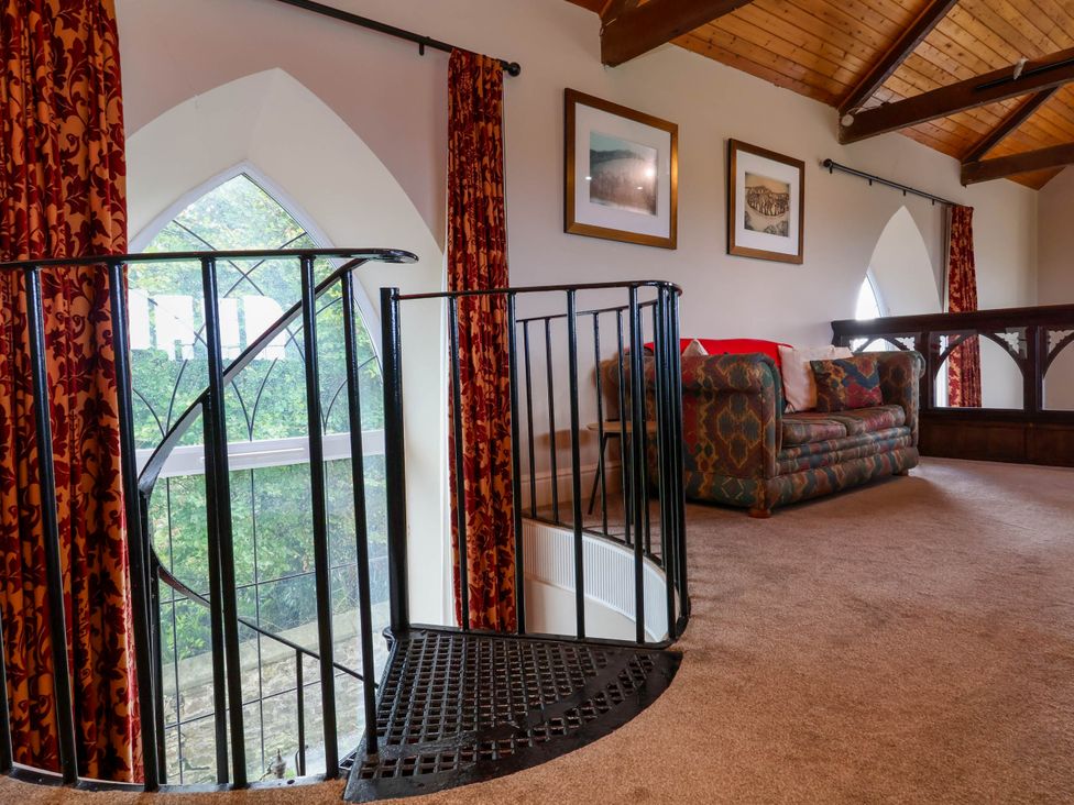 A living room with a spiral staircase and a sofa at Old Chapel in Clovelly