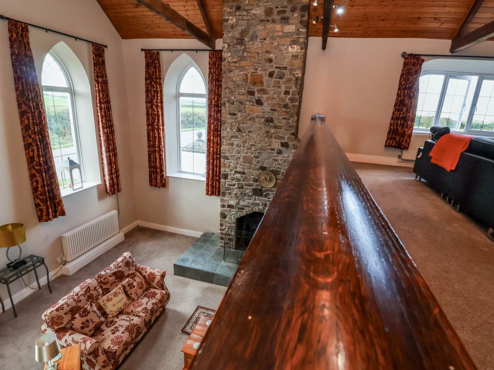 A living room with a stone wall and large windows at Old Chapel in Clovelly