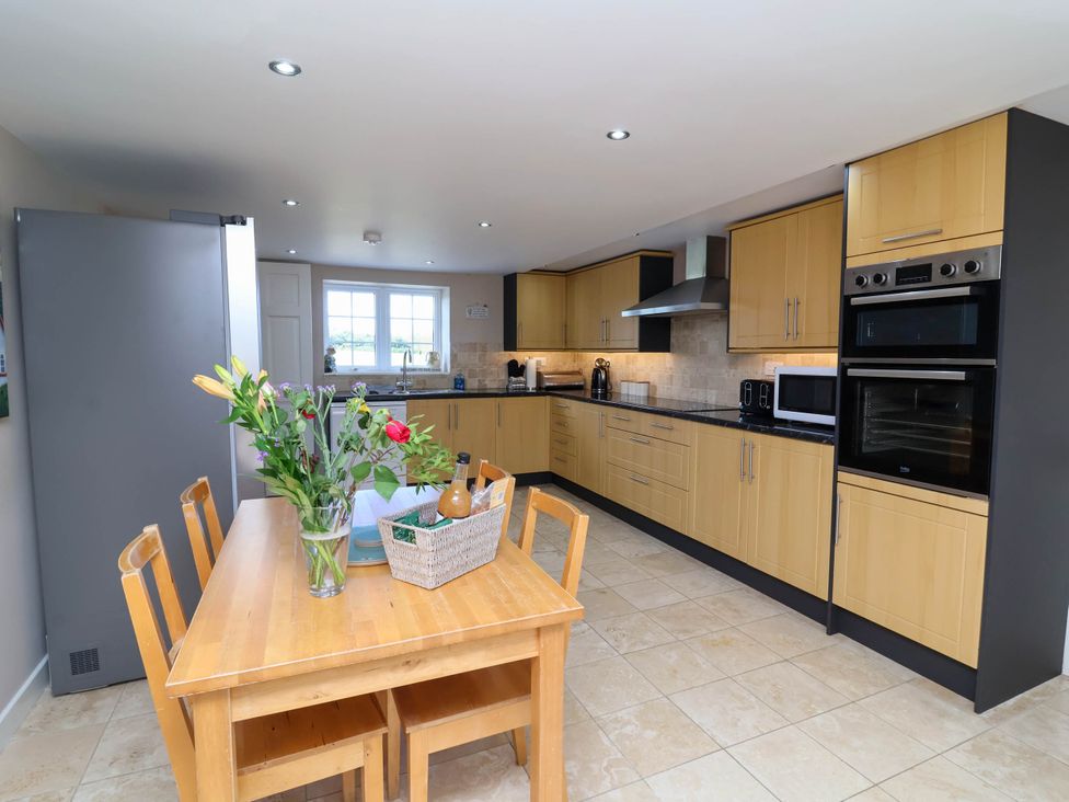 A kitchen with wooden cabinets and a dining table at The Old Chapel in Clovelly