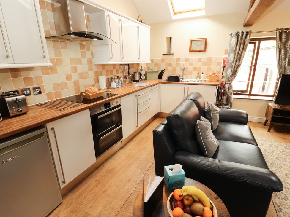 A kitchen with a sofa and dining table at Stable Cottage Bolton Low Houses