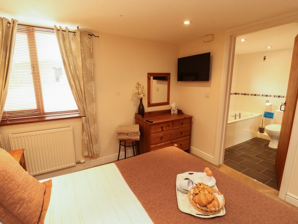 A bedroom with a bed and television at Stable Cottage in Bolton Low Houses