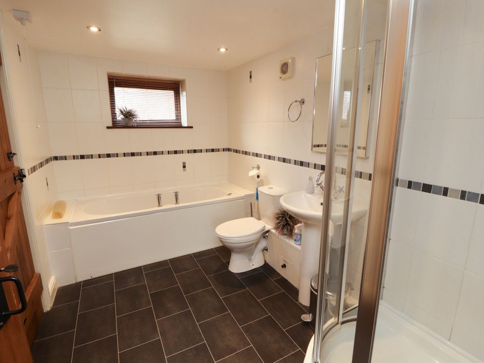 A bathroom with a bath tub, shower, toilet, and sink at Stable Cottage in Bolton Low Houses