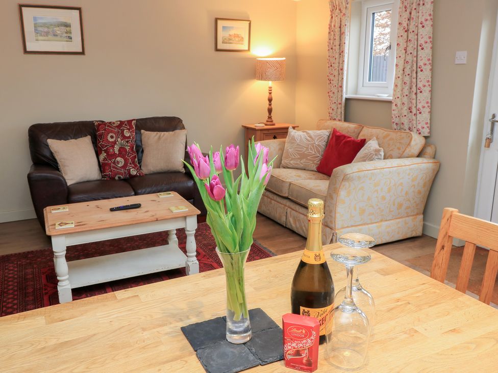 A living room with a sofa, armchair, and coffee table at Garden Cottage, Rode Farm, Rode