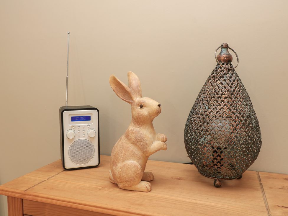 A radio, rabbit statue, and decorative lantern on a wooden surface at Garden Cottage, Rode Farm in Rode