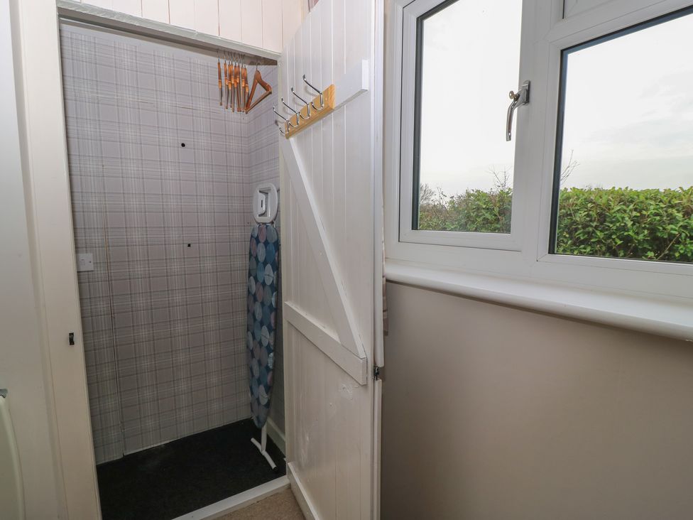 A laundry room with an ironing board and window at Garden Cottage, Rode Farm in Rode