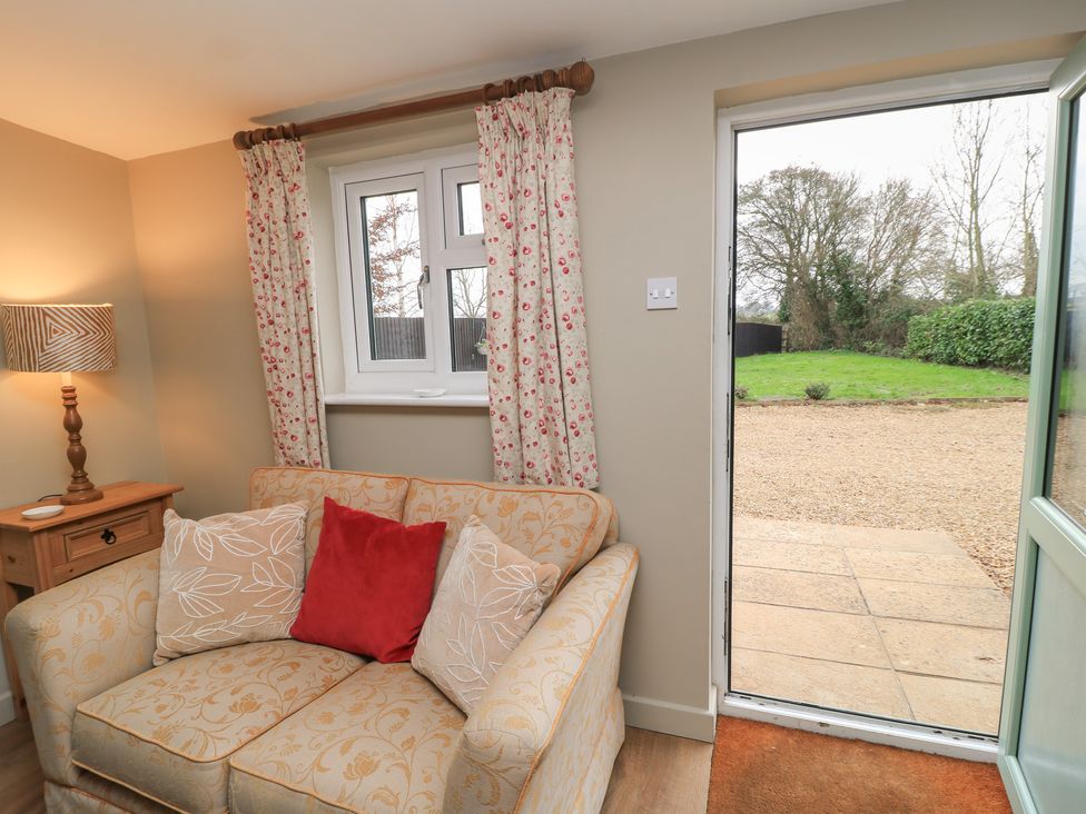A living room with a sofa and a door leading outside at Garden Cottage, Rode Farm in Rode