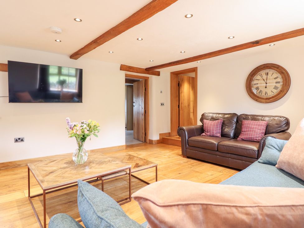 A living room with a sofa, coffee table, and television at Ty Gwyn Llangwm near Bala