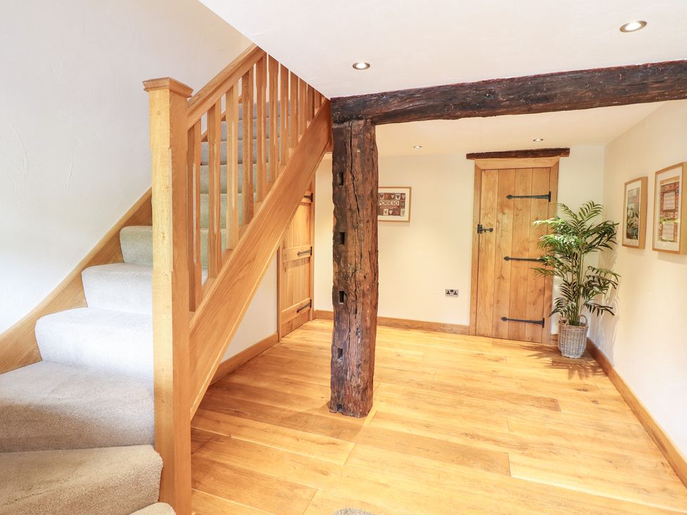 A hallway with a staircase and wooden door at Ty Gwyn in Llangwm near Bala