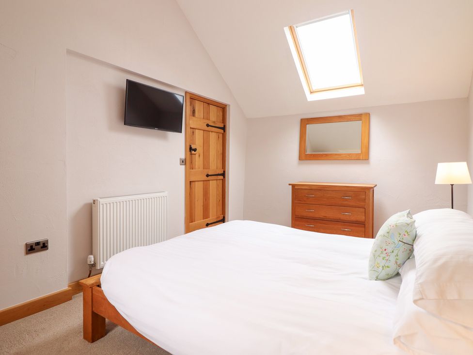 A bedroom with a bed, wardrobe, and television at Ty Gwyn in Llangwm near Bala