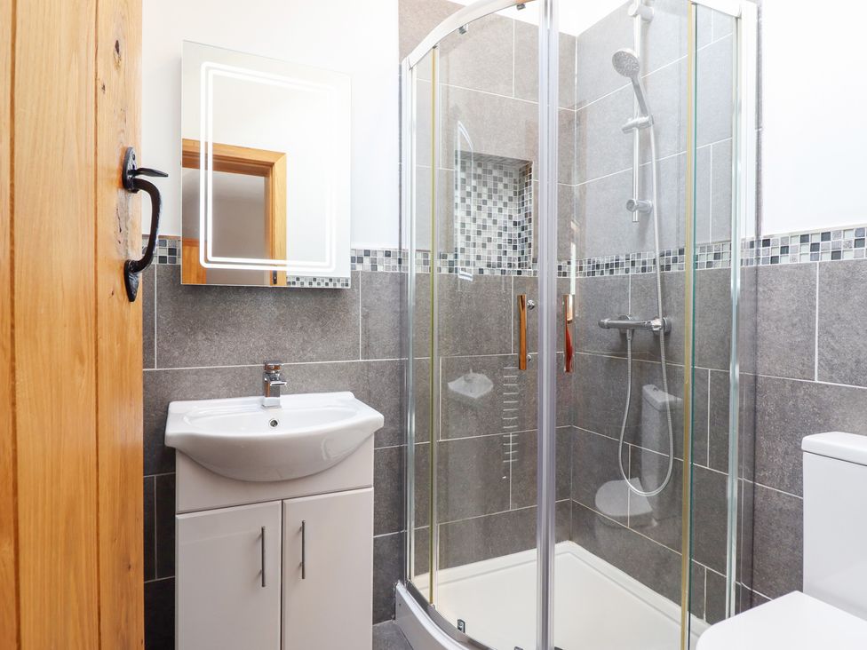 A bathroom featuring a shower, toilet, and sink at Ty Gwyn Llangwm near Bala