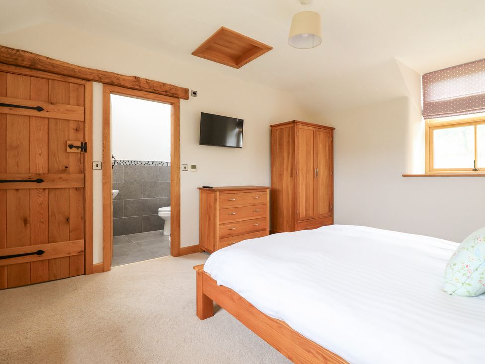 A bedroom with wooden furniture and a bathroom door at Ty Gwyn in Llangwm near Bala