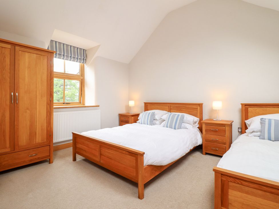 A bedroom with two beds and a wardrobe at Ty Gwyn in Llangwm near Bala