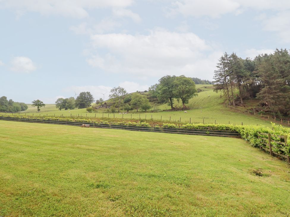 A grassy area with a fence and vineyard in Llangwm near Bala