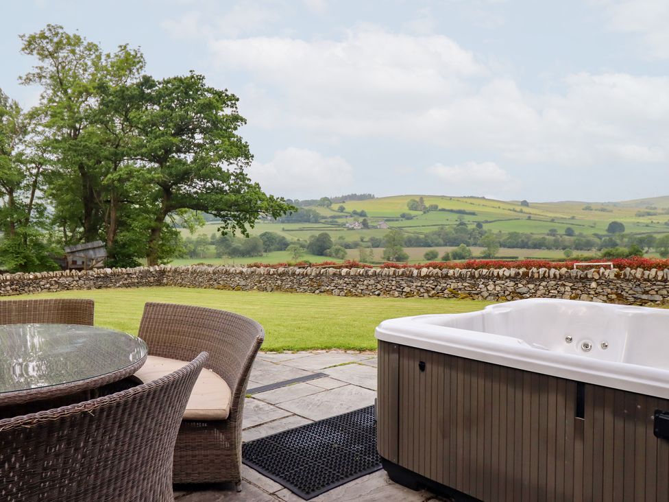 An outdoor area with a table and chairs beside a hot tub at Ty Gwyn in Llangwm near Bala