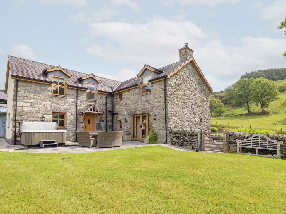 A house with a hot tub and patio furniture at Ty Gwyn in Llangwm near Bala