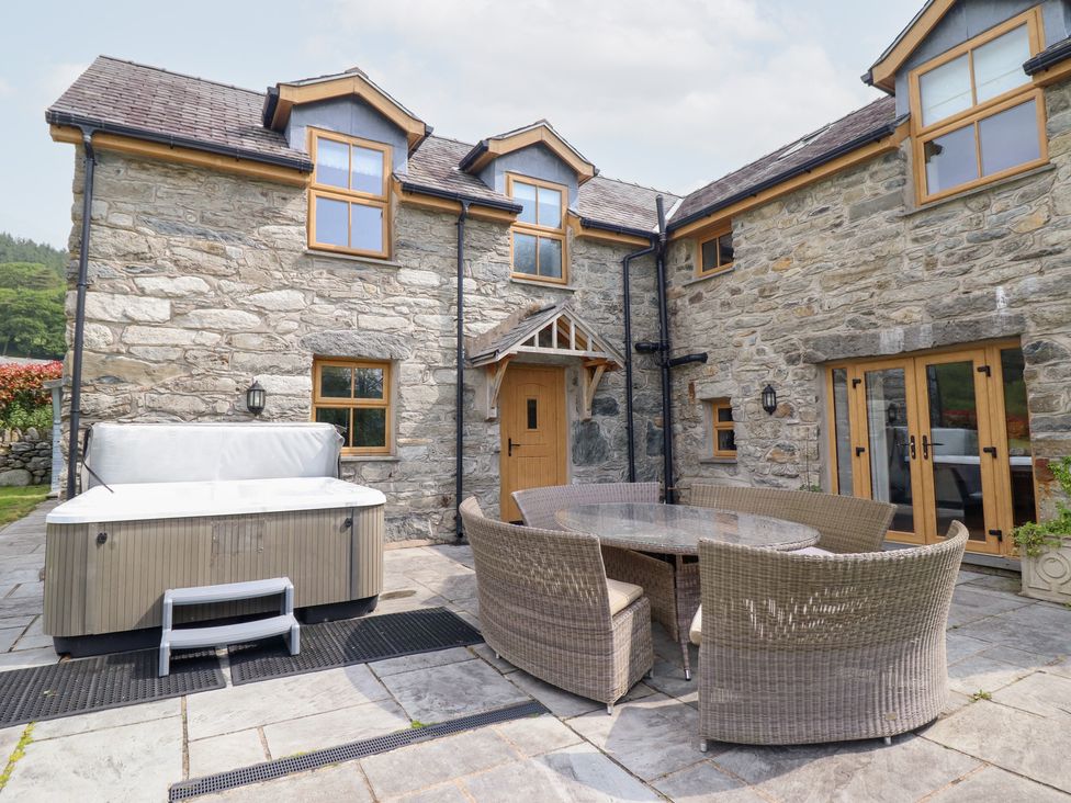 An outdoor area with a hot tub and dining set at Ty Gwyn Llangwm near Bala