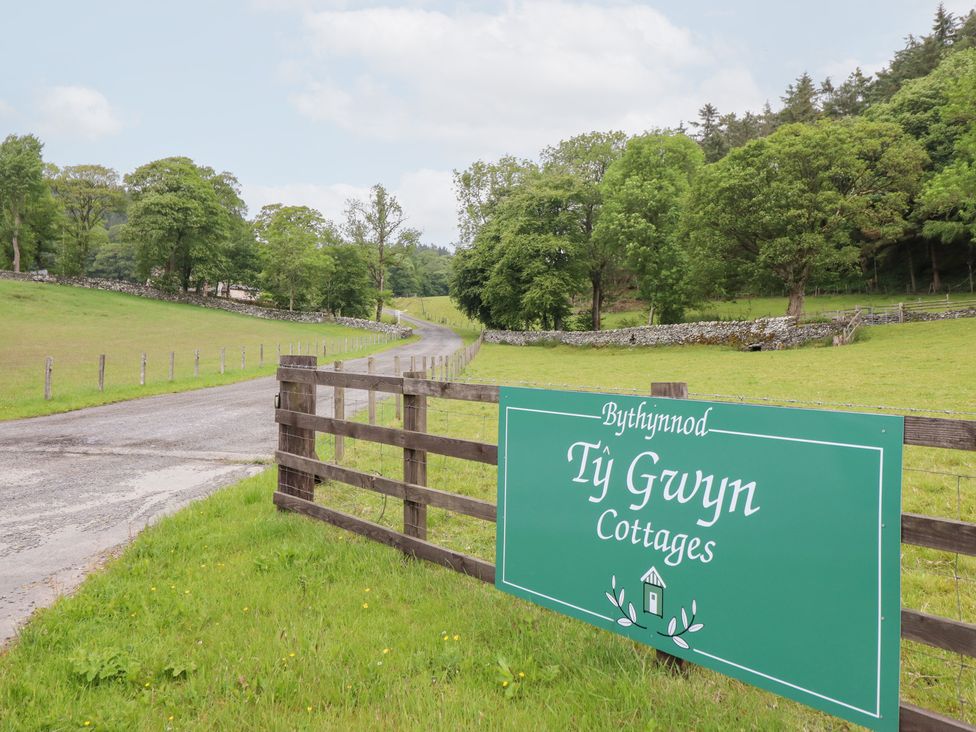 A sign for Ty Gwyn Cottages near a road in Llangwm near Bala
