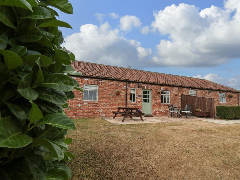 A brick building with a table and chairs outside at Beacon in Gerrick near Moorsholm