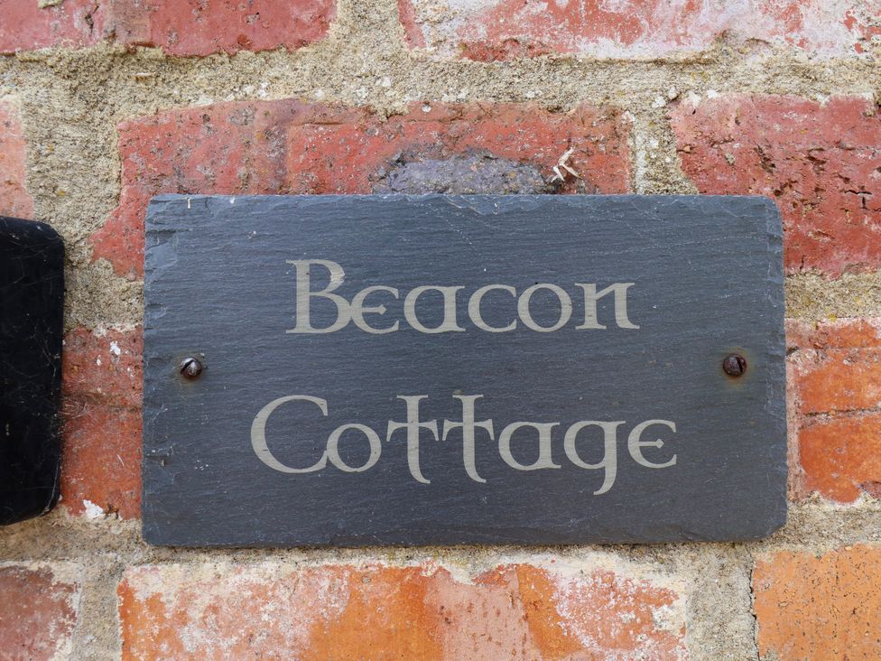 A sign that reads 'Beacon Cottage' attached to a brick wall at Beacon in Gerrick near Moorsholm