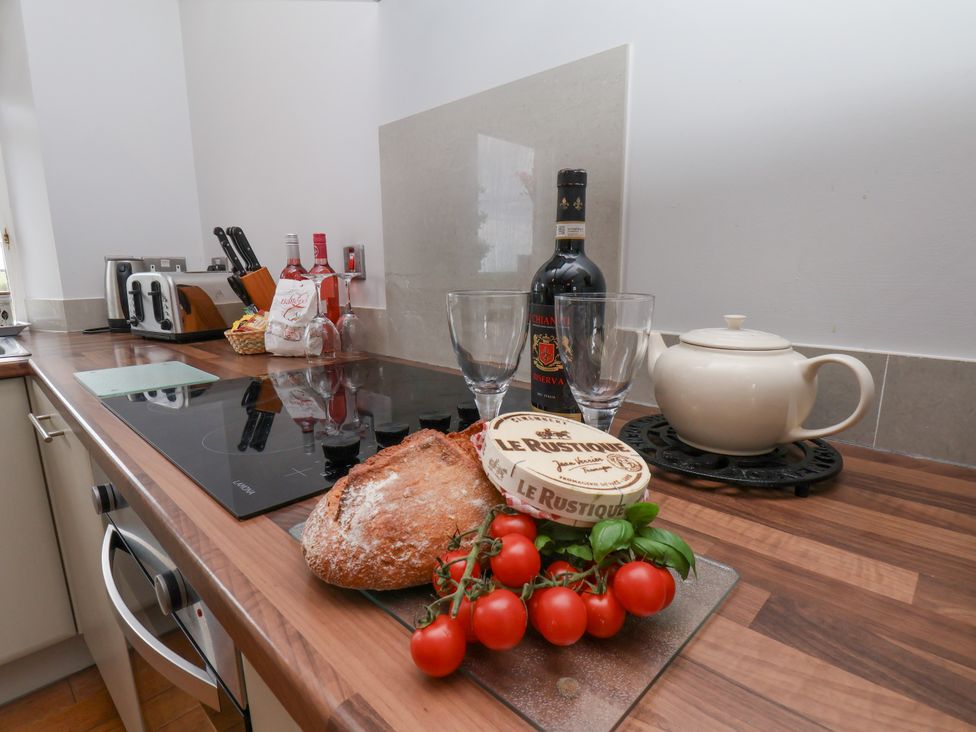 A kitchen with a countertop featuring bread, tomatoes, glasses, and a teapot at Beacon in Gerrick near Moorsholm