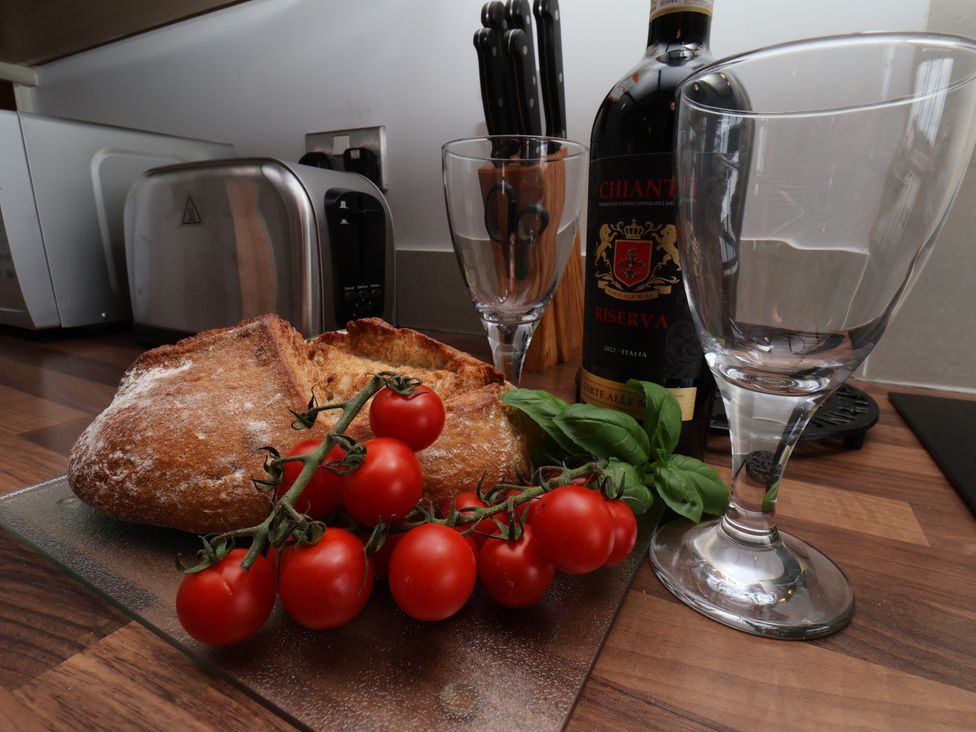 A kitchen with bread, tomatoes, wine glasses, and a wine bottle at Blakey in Gerrick near Moorsholm