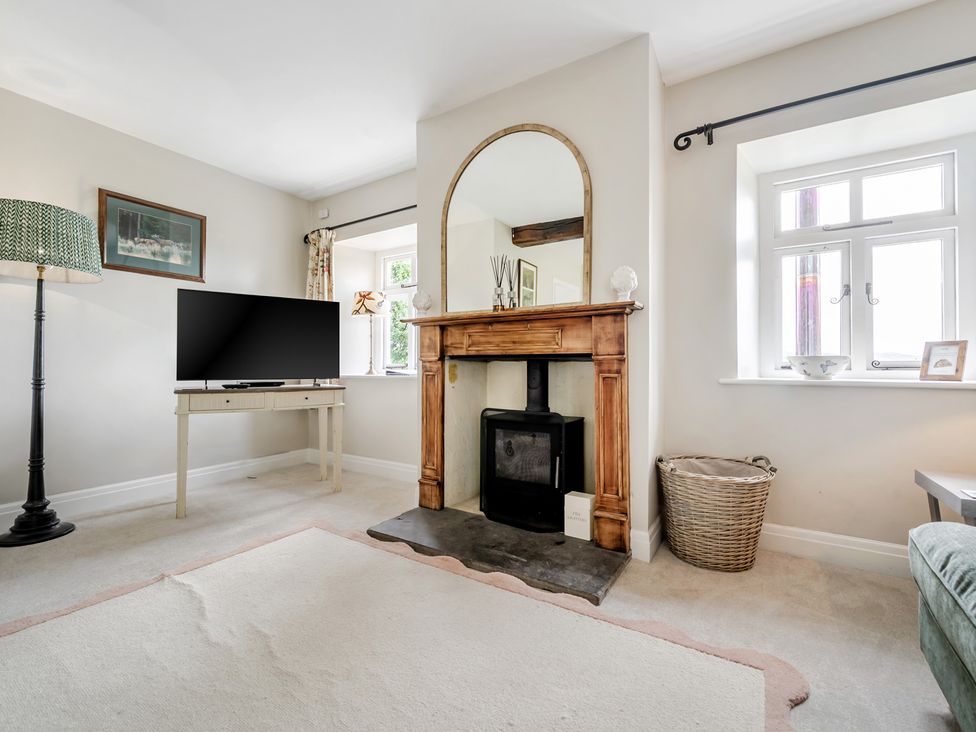 A living room with a television and fireplace at Dove Cottage at the Graythwaite Estate near Hawkshead