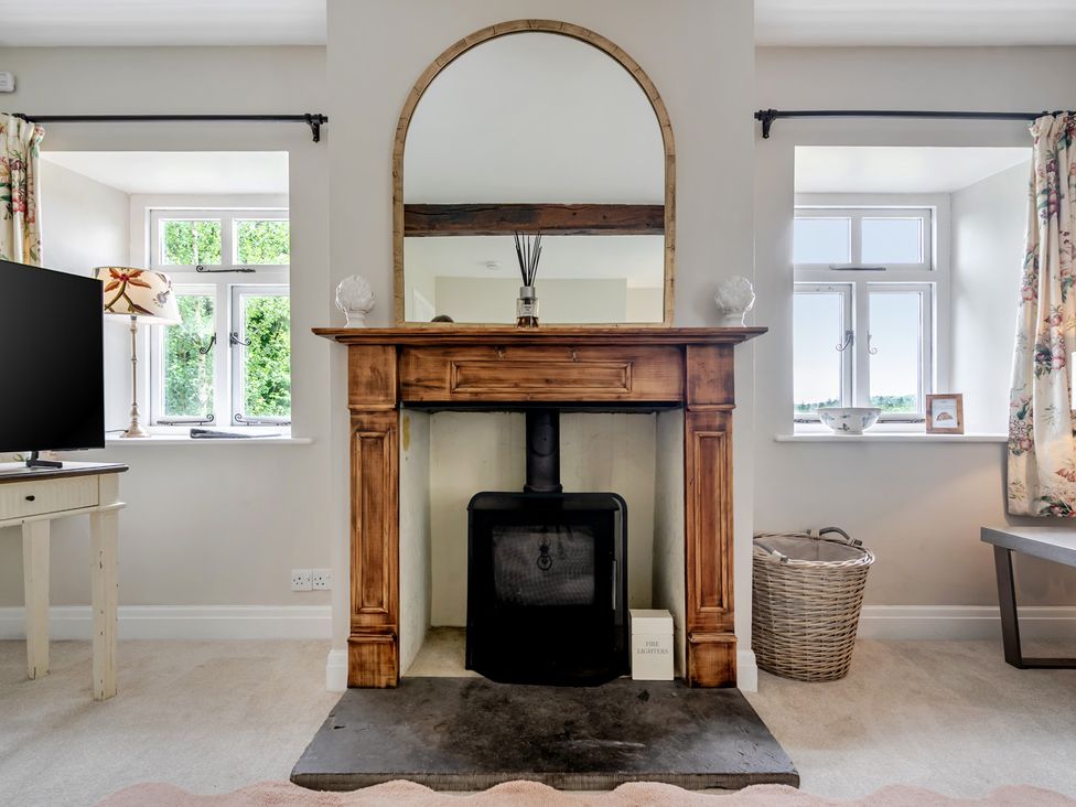A living room with a fireplace and television at Dove Cottage at the Graythwaite Estate near Hawkshead