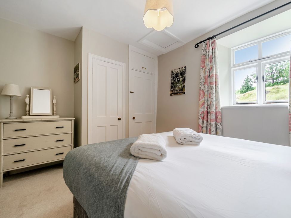 A bedroom with bed, dresser and window at Dove Cottage at the Graythwaite Estate near Hawkshead